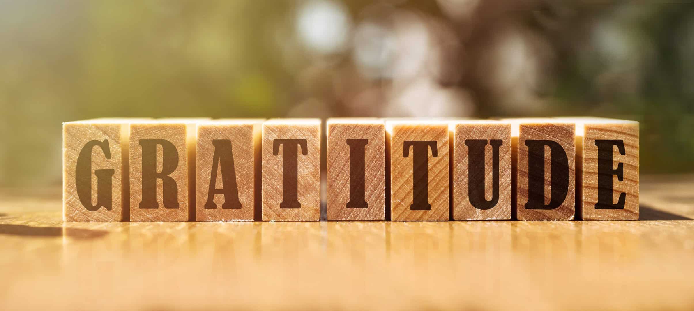 Gratitude word written on wood block. gratitude text on wooden table for your desing, concept.